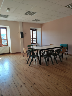 Salle avec table, chaises, haut-parleurs et fenêtres.