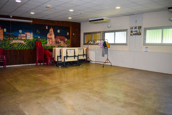 Salle avec chaises, table, étagère, porte-manteau, et peinture murale.