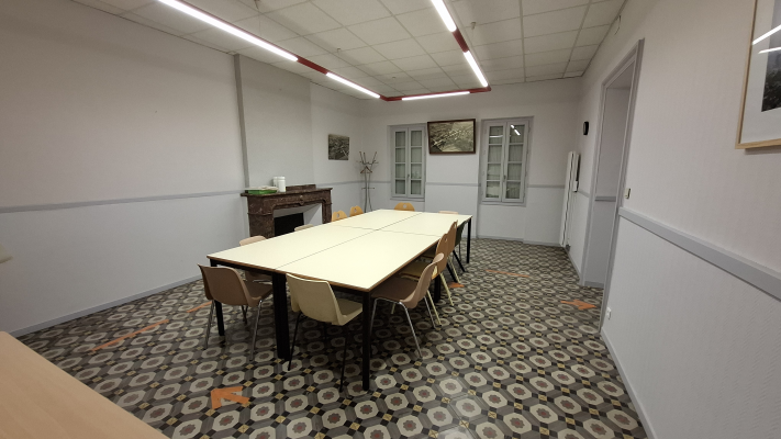 Salle avec table, chaises, cheminée, tableaux et porte.