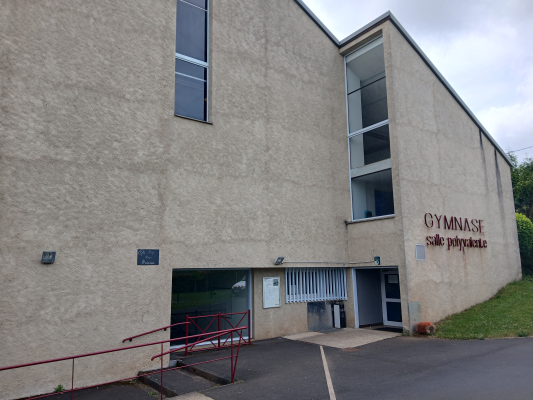 Bâtiment avec entrées, rampes et panneaux "Gymnase salle polyvalente".