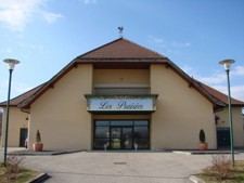 Bâtiment avec enseigne "Les Pâtisseries", entrées vitrées, toits en pente et lampadaires.