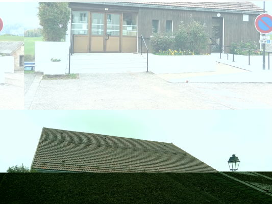 Bâtiment avec entrée, parking et lampadaire.