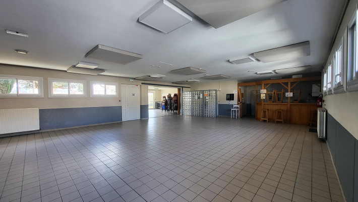 Salle spacieuse avec bar, tabourets, distributeur automatique et portes.