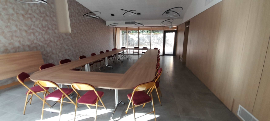 Salle de réunion avec table en U, chaises, canapé, et vidéo projecteur.