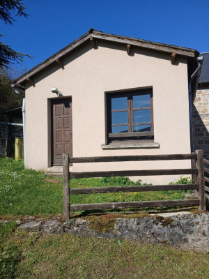 Maison avec porte en bois, fenêtre, clôture en bois et terrain herbeux.