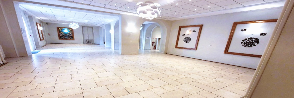 Grand espace intérieur avec carrelage, luminaires suspendus, cadres et portes.