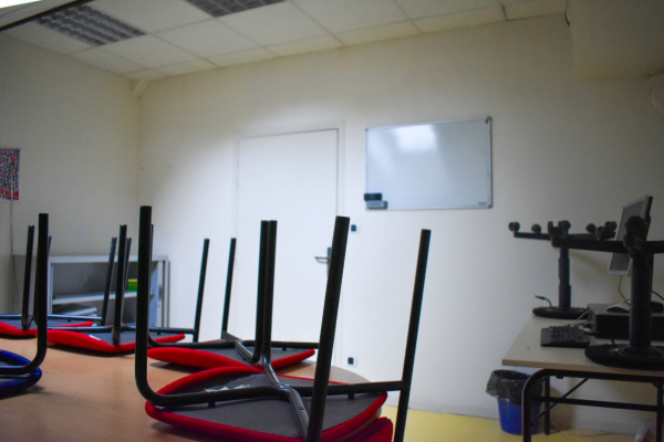 Salle avec table, chaises à ballon, tableau blanc, écran, ordinateur et matériel audio.