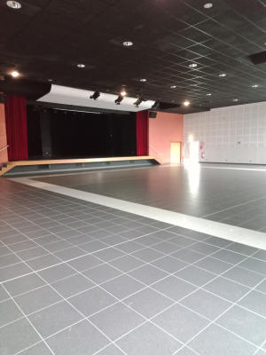 Salle avec scène, projecteurs et murs colorés.