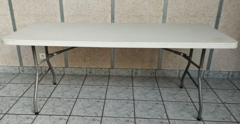 Table blanche avec tréteaux et pieds métalliques sur carrelage.