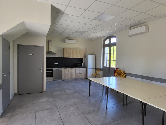 Cuisine avec table, chaises, frigo, four, meubles, placard, hottes et climatiseurs.