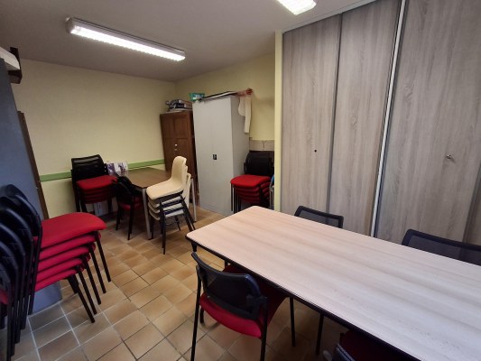 Pièce avec table, chaises, placard, étagères, porte-manteau.