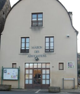 Bâtiment avec enseigne "Maison des Associations", porte vitrée, fenêtres et panneaux d'affichage.