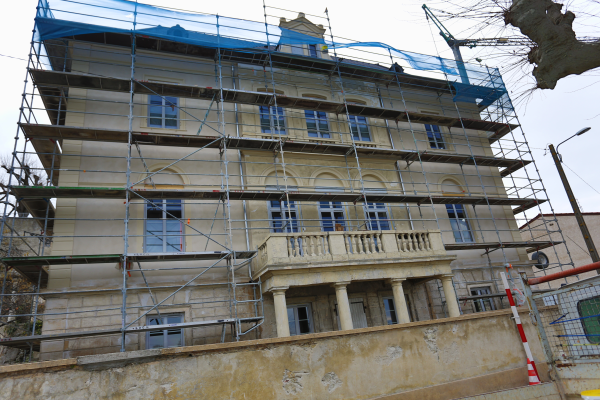 Bâtiment en rénovation avec échafaudages, fenêtres et balcons.