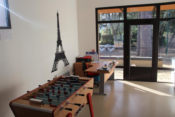 Pièce avec table de football, bureau, chaise, étagères et porte vitrée.