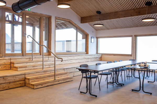 Salle avec tables, chaises, gradins, rambarde et fenêtres.