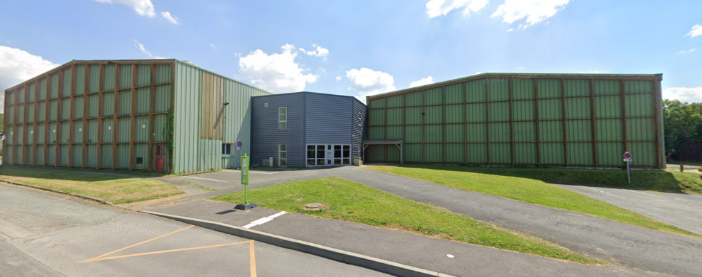 Bâtiment industriel avec trois sections, parking et panneaux de signalisation.