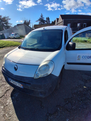 Camionnette blanche avec logo, plaque d'immatriculation visible.
