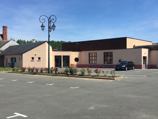 Bâtiment avec lampadaire, plantes et voiture.