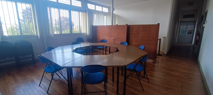 Salle de réunion avec table, chaises, paravents, radiateur.