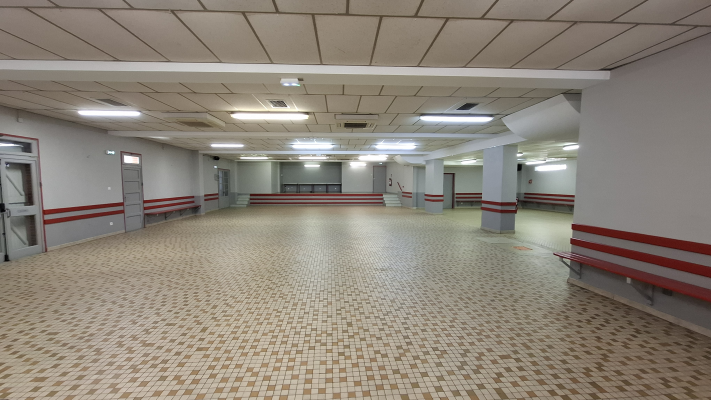 Salle vide avec bancs, portes et éclairage au plafond.