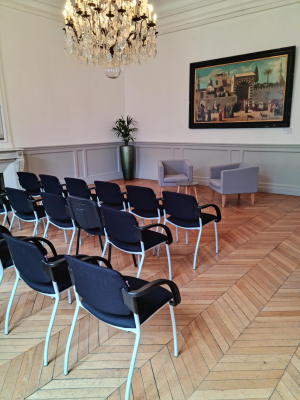 Salle avec chaises, table, lustre, plante, tableau et moulures.