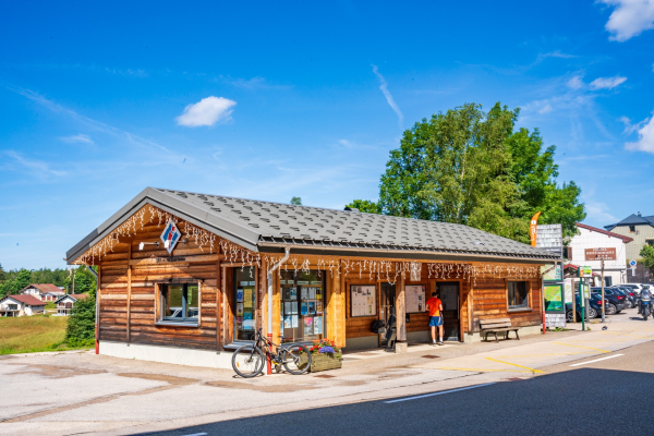 Maison en bois avec bicyclette, banc et arbres.