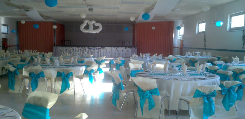 Salle avec tables, chaises, nappes, serviettes et décorations.