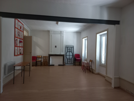 Salle avec chaises, tables, radiateur, tableau d'affichage et cheminée.