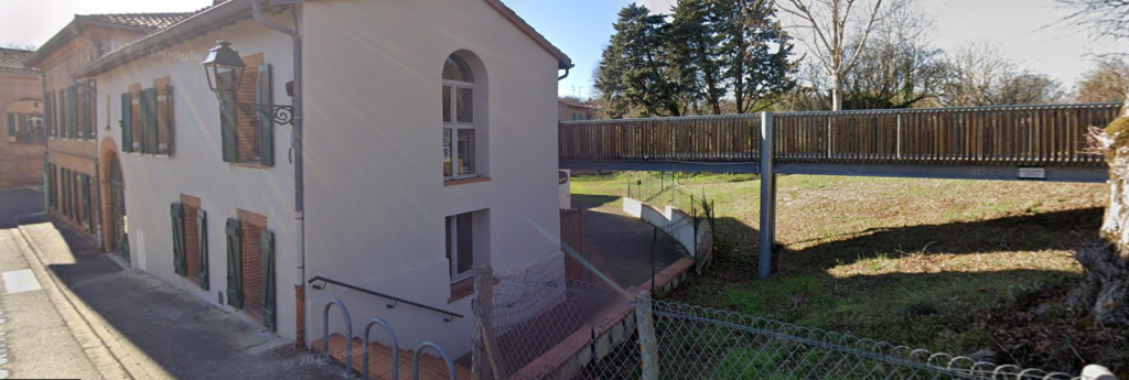 Bâtiment avec fenêtres, grilles, grille et arbre en arrière-plan.