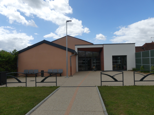 "Bâtiment avec entrées, bancs, lampadaire et chemin piétonnier."