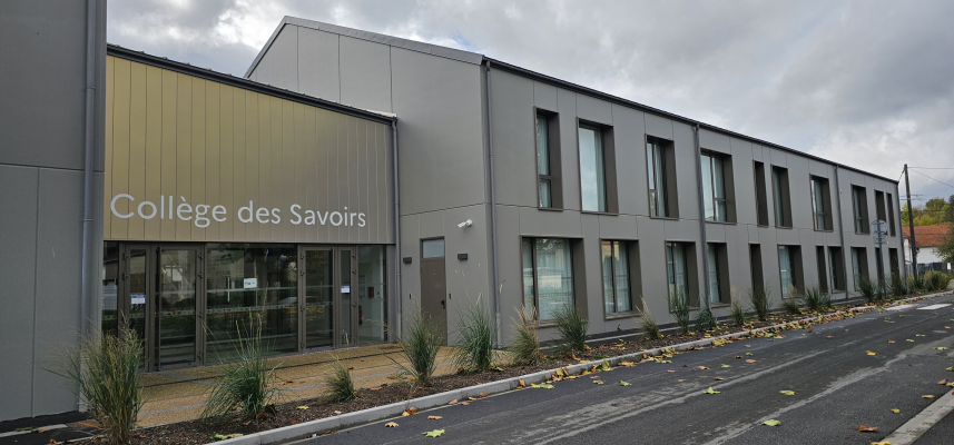 "Bâtiment gris moderne avec façade vitrée, portant l'enseigne 'Collège des Savoirs', bordé de plantes."