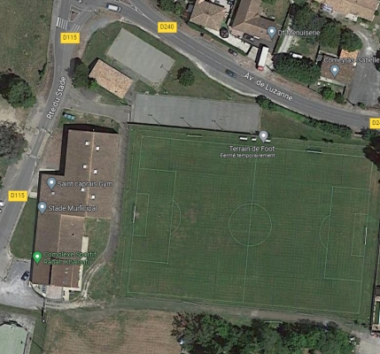 Vue aérienne d'un terrain de football et d'un stade avec des bâtiments adjacents et des routes.