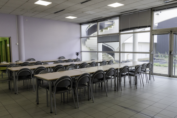 Salle avec tables, chaises, et fenêtres vitrées.