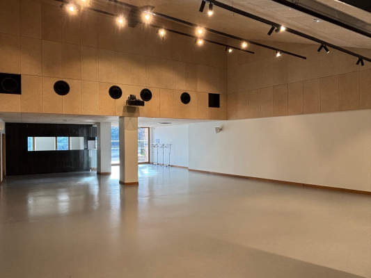 Salle vide avec éclairage, haut-parleurs, et porte vitrée.