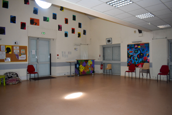 Salle avec chaises, tableaux, porte, fenêtre et matériel de jeu.