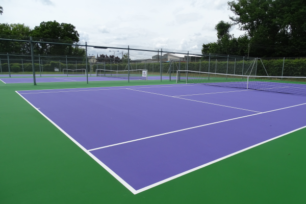 Terrain de tennis avec filet et clôture.