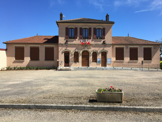 Bâtiment avec toiture rouge, fenêtres et portes en bois, drapeaux, jardinière avec fleurs.