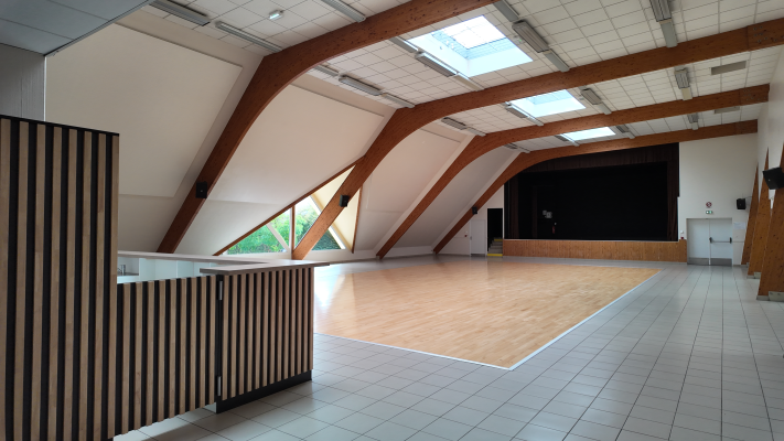 Salle avec plancher en bois, murs en brique, fenêtres, comptoir et porte.