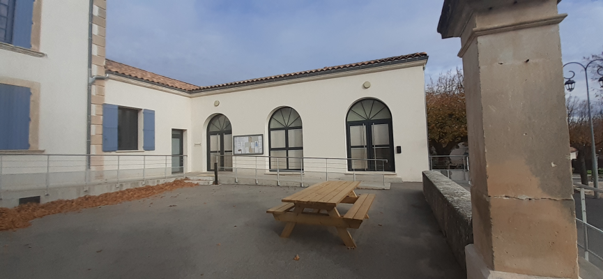 Bâtiment avec entrée, fenêtre et banc de pique-nique extérieur.