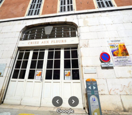 "Grandes portes vitrées, enseigne "CRIEE AUX FLEURS", panneaux d'affichage, parcmètre."