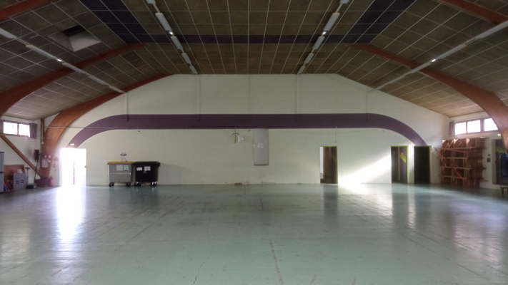 Salle spacieuse avec sol lisse, piliers, éventail, portes et étagères.
