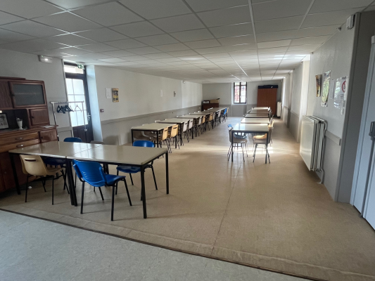 Salle avec tables, chaises, armoire et radiateur.