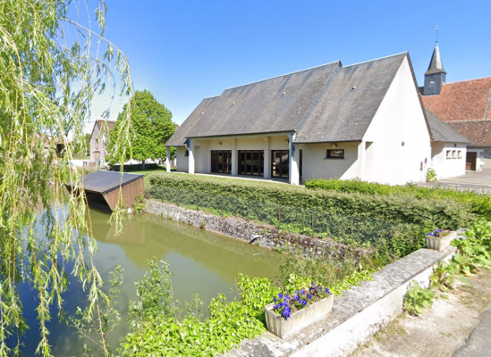 Maison près d'un étang, avec clocheton à l'arrière-plan.