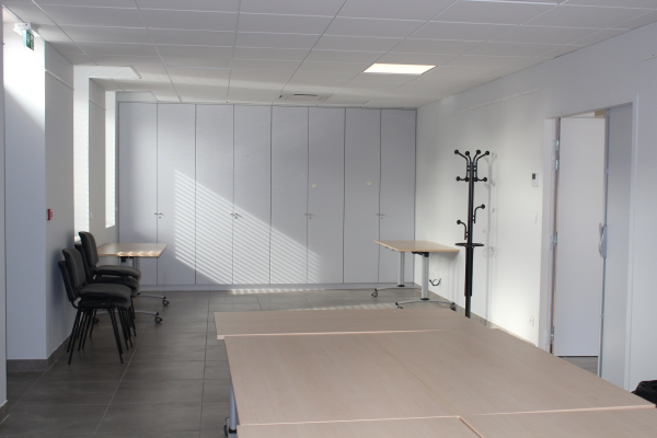 Pièce vide avec tables, chaises, placards, porte-manteau et porte.