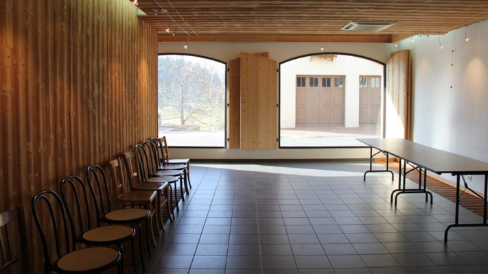 Salle avec tables, chaises, portes en bois et vue extérieure.