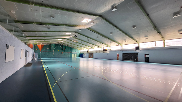 Salle de sport avec paniers de basket, murs d'escalade et éclairage.