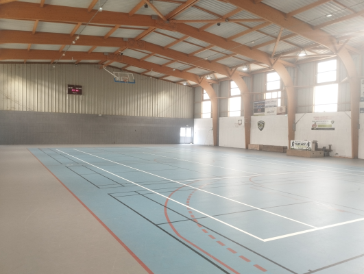 Salle de sport avec panier de basket, terrain de basket et bancs.