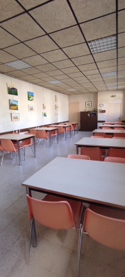 Salle avec tables, chaises, tableaux, armoire et lumières.
