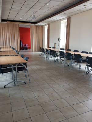 Salle avec tables, chaises, rideaux, horloge et luminaires.