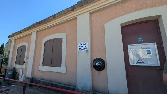 Bâtiment avec fenêtres, porte, sonnette et panneau "Salle Gabriel Masini".